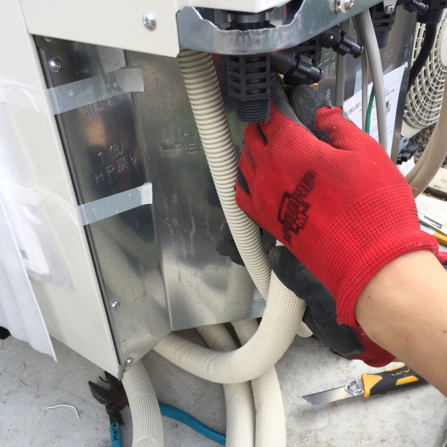 エコキュートの配管接続部を施工中の様子。断熱材を巻いた配管と作業中の手元